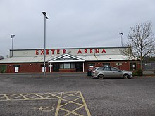 Image of the front of the arena stand, showing the car park and front doors