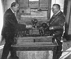 Gonzalo, Torres Quevedo's son, showing El Ajedrecista to Norbert Wiener at the 1951 Paris Cybernetic Congress Gonzalo showing El Ajedrecista to Norbert Wiener.jpg