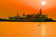 A white building with one minaret on an island seen at sunset