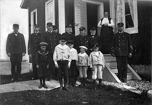 Kronolotsar i uniform med familjemedlemmar, cirka 1890. Lotsarna bar sjöunderofficerares gradbeteckningar i form av chevroner på underärmarna. Till skillnad mot flottan pekade dock spetsarna nedåt.