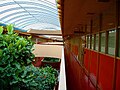 Фотография интерьера общественного центра округа Марин. Двухэтажный атриум в крыше с озеленением, несколькими острыми углами и множеством красных и розовых цветов.