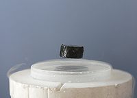 A magnet levitating above a high-temperature superconductor. Today some physicists are working to understand high-temperature superconductivity using the AdS/CFT correspondence. Meissner effect p1390048.jpg