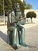 A photo of bronze statue of sitting man holding a gastropod shell