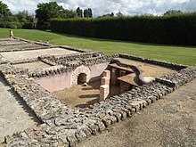 Photographie des vestiges de pièces antiques avec au premier des empilements de briques pour surélever un plancher disparu.