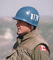 a person in a military uniform wearing a United Nations blue helmet