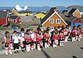 . Skulebarn i tradisjonelle inuittiske klede held grønlandske flagg på første skuledag