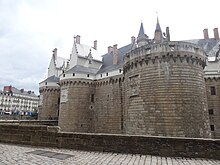 Colour photograph of the ramparts and towers of a castle in the middle of the city.