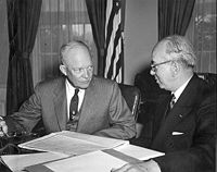 Schwarzweißfoto: Eisenhower und Strauss sitzen an einem Tisch, auf dem Akten ausgebreitet sind.