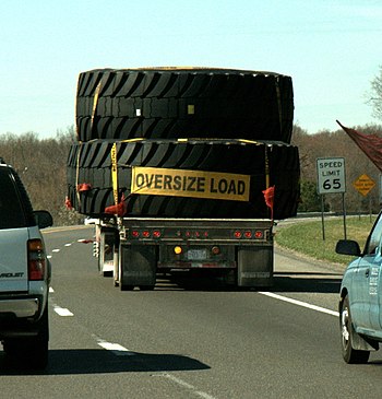 English: Three huge tires on a flatbed truck -...