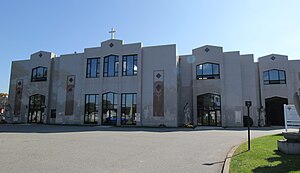 Two-story white building topped with a Christian cross