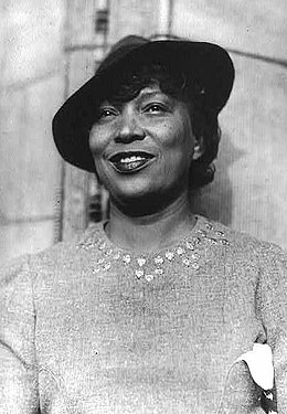 portrait d'une femme noire américaine avec un petit chapeau posé de biais.
