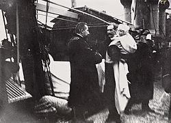 Kong Haakon VII ankommer Norge med skip fra København 25. november 1905 med sønnen kronprins Olav (senere kong Olav) på armen. Statsminister Christian Michelsen ønsker den nye kongen velkommen.