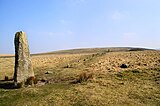 Een van de drie menhirs van Drizzlewoodcombe bij een stenenrij naar een steenkist, rechts is een grafheuvel te zien, Verenigd Koninkrijk