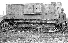 An early armoured vehicle: the rectangular body is made of riveted plates and has a number of empty gun ports. It is carried on full-length caterpillar tracks.