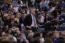 Mike D'Antoni, debout. Des spectateurs figurent au premier rang et en arrière plan.