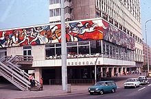 Murals displaying the Marxist view of the press on this East Berlin cafe in 1977 were covered over by commercial advertising after Germany was reunited. Press Cafe in East Berlin on Alexanderplatz, 1977.jpg