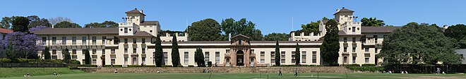 A panoramic photograph of the Physics Building  from across playing fields called The Square.