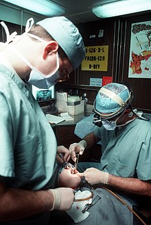 An oral surgeon and dental assistant removing a wisdom tooth Dental surgery aboard USS Eisenhower, January 1990.JPEG