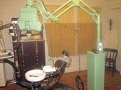 Fauteuil de dentiste, à gauche roulette électrique à câble de début de siècle, appareil à rayons X ultérieur (en vert).