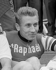 A man wearing a cycling jersey while smiling.