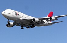 A Boeing 747–400 aircraft in mid air, with blue sky in the background