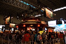 A photo of the Capcom area at Tokyo Game Show 2010; the middle portion of the picture shows their Monster Hunter showcase, while the Ace Attorney Investigations 2 showcase can be seen on the right, and includes an inflatable figure of the "Steel Samurai" character.