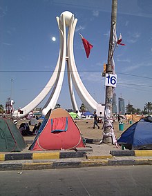 A white structure by a road with tents in the foreground.