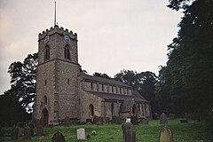 A small church with a square Ashlar tower, in the Early English style. The tower is to the left, the nave to the right, and we are looking somewhat obliquely at it. The church is ringed by medium size trees, and a large Yew dominates the right of the picture, in the middle distance. A handful of mismatched gravestones dot the grassy nearground of the picture.