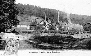 Photo noir et blanc montrant une petite usine avec deux cheminées carrées.