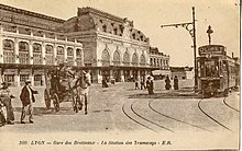 Carte postale de 1900, montrant une gare d'architecture haussmannienne devant laquelle est aménagée une station de tramway.