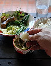 Le khao niao (riz gluant) se mange avec la main droite. En lui donnant une forme aplatie, il est plus facile de prendre des mets comme le nam phrik num (pâte de piment vert grillé). Les autres aliments sont : la sai ua, le krachiap khiao (gombo), le dok khae (fleurs de sésbania) et le chaom (feuilles d'acacia).