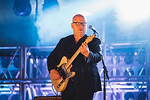 Black Francis playing guitar onstage, in front of a microphone