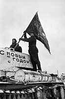 Tankista vyzdvihuje vlajku na tank a připravuje se na příchod na frontu obrany Moskvy. Nápis na tanku je v překladu "Šťastný nový rok", 31. prosince 1941.