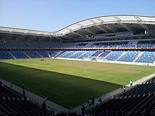 An all-seated roofless stadium with a football pitch.