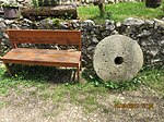 Дрвена клупа и стари воденични камен