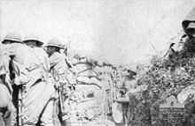 Photographie noir et blanc de soldats debout dans une tranchée, regardant vers la gauche