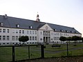 Schulgebäude mit Turnhalle und Aula-Anbau sowie umgebendem Freiraum und Fußgängerbrücke