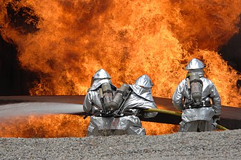 ثلاثة رجال من القُوَّات الجويَّة الأمريكيَّة، في دورةٍ ميدانيَّةٍ لِإطفاء ومُكافحة الحرائق