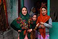 Kashmirske jenter med skaut samla i halsen med sikkerheitsnål eller ei hand.