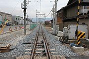 大泉東駅跡（桑名方より見る）線路右側は廃止直前ホーム位置、線路左側道路部分は旧駅舎・旧行き違い線ホーム位置。曲線改良による線路直線化後の姿