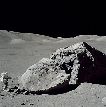 Astronauta próximo a uma grande rocha lunar