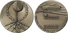 Photo de l'avers et du revers d'un médaille avec barbelés et bras décharnés sur l'avers, et la phrase « Le peuple juif reconnaissant » au revers.
