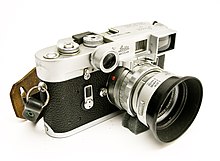 Zdjęcie aparatu Leica M4 z obiektywem Summicron 50mm f/2. Aparat został tak sfotografowany, że wszystko wokół niego jest białe.