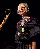 A picture of singer-songwriter Sia, smiling while performing