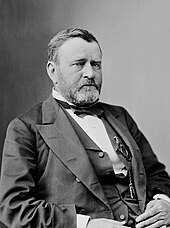 Photographie noir et blanc en buste de trois-quart d'un homme blancportant une moustache et une barbe en costume officiel de président