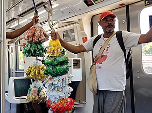 Um vendedor de balas e amendoim dentro do trem. Ele carrega seu gancho expositor onde todas as balas e amendoins são pendurados.