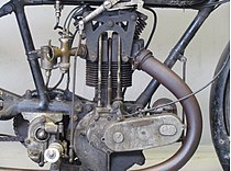 Het kopklepblok van het TT Model uit 1923. De buitenliggende stoterstangen, tuimelaars en klepveren zijn hier goed te zien. De bowdenkabel rechts bedient de kleplichter.