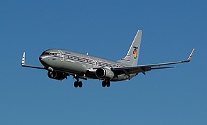 Left side view of the front of an aircraft painted dark gray with blue sky in the background.