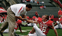 Photograph of Schiano interacting with a player during pre-game warmups