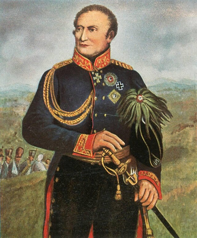 Black and white print shows a clean-shaven man holding a sword with a bicorne hat tucked under his left arm. He wears a plain dark military uniform with an Iron Cross and several other decorations.